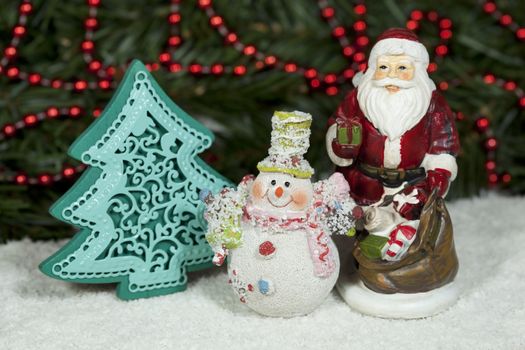 Santa Claus with gifts under the Christmas tree and snowman.