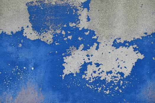 Flakes of old vintage grungy bright vivid blue paint on grey concrete wall