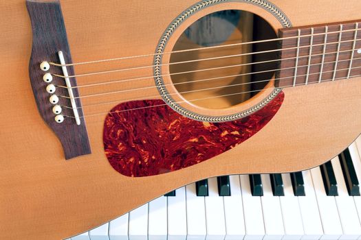 Acoustic Guitar sitting on Piano Keyboard Closeup