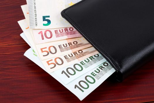 Wallet with European money on a wooden background