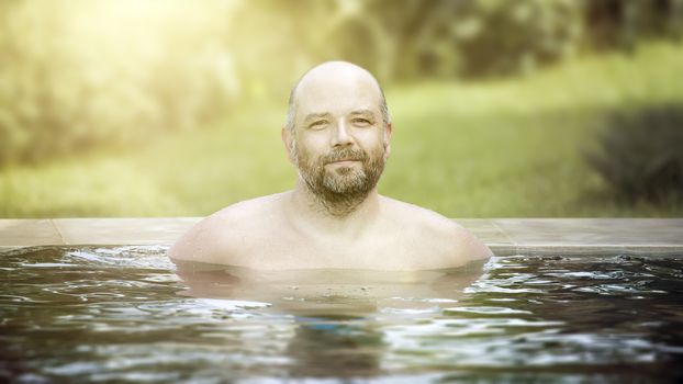 An image of a middle age man relaxing at the pool