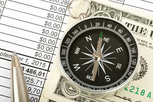 Compass with cash and pen on bills background, closeup