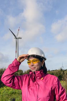 Engineer woman checking production, with laptops, wind turbines on the site.