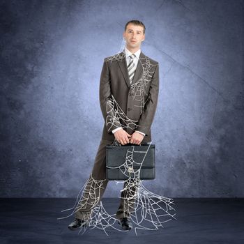 Businessman in spider web looking at camera on grey background 