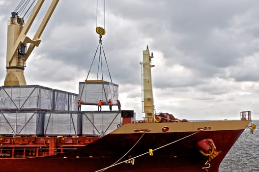 Crane loading cargo in to ship in harbor