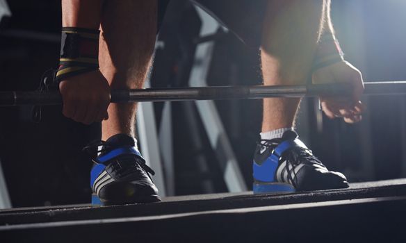 Hands of man ready to lift barbell at fitness club