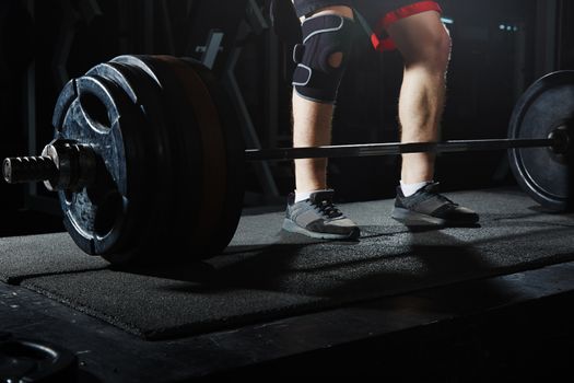 Man at the heavy barbell in fitness club. Close-up view