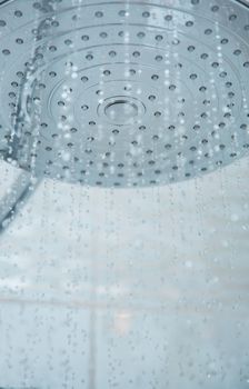 Shower head with flowing water. Close-up vertical photo