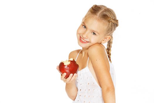 Cute little girl in a white dress bites red fresh apple