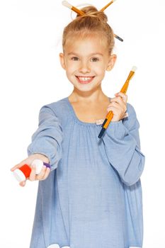 Little girl painter in a blue dress with paints and brushes