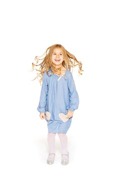 Jumping little girl in a blue dress with flying curls