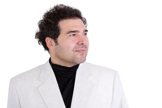Slightly grinning confident man with curly hair and stubble wearing white jacket and polo-neck shirt looking off into the distance