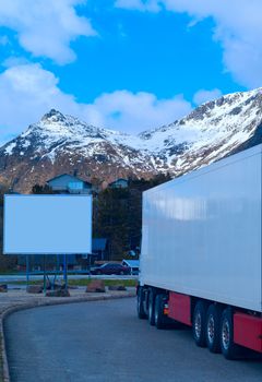 White refrigerated truck on background of the mountains and big white billboard