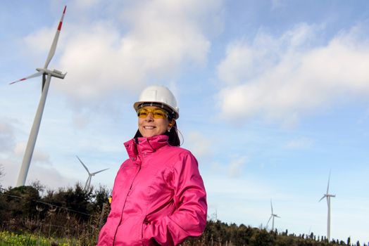 Engineer woman checking production, with laptops, wind turbines on the site.