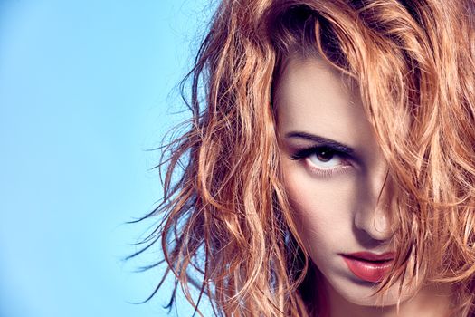 Beauty portrait woman with wet wavy hair. Playful sexy redhead model, natural makeup, fashion.Sensual attractive girl provocative looks, long eyelashes, copyspace, blue.People face closeup. Confidence