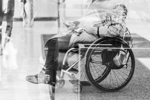 Handicapped male businessman on a wheelchair using smartphone. Disabled people active for life. Black and white image.