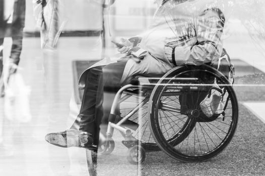 Handicapped male businessman on a wheelchair using smartphone. Disabled people active for life. Black and white image.