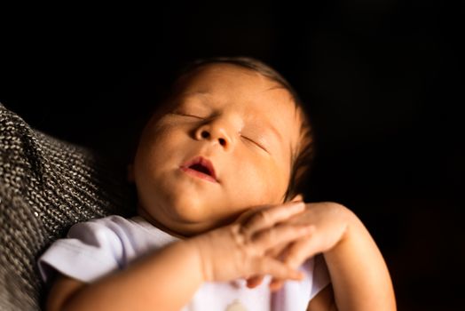 A Newborn Sleeps in his Father's Arms with black background.