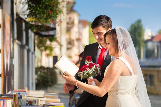 Bride and groom. Portrait of a loving wedding couple reviewing vintage books in antique book shop in medieval city center of Ljubljana, Slovenia.