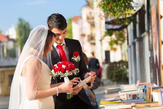 Bride and groom. Portrait of a loving wedding couple reviewing vintage books in antique book shop in medieval city center of Ljubljana, Slovenia.