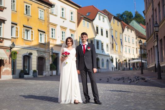 Bride and groom. Portrait of a loving wedding couple, holding hands, walking down cobbled street in medieval city center of Ljubljana, Slovenia.