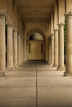 Old stone path way lined with stone colums leading to an old wooden door.