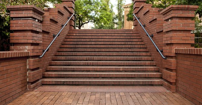 Beautiful red brick paved stair case with hand rails.