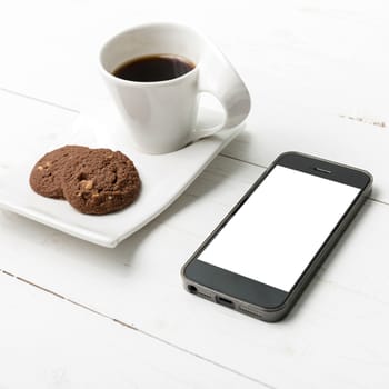 coffee cup with cookie and phone on white wood background