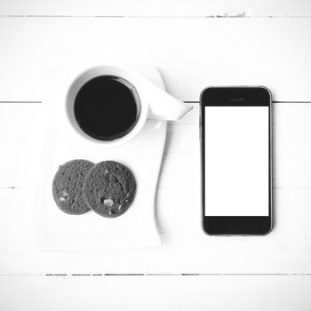 coffee cup with cookie and phone on white wood black and white color