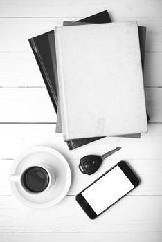 coffee cup with phone,car key and stack of book on white wood table black and white color