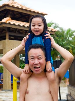 Man carrying his little daughter on shoulders in swimming pool 