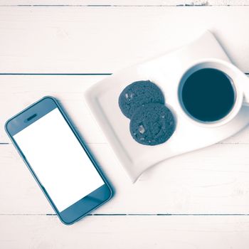 coffee cup with cookie and phone on white wood background vintage style