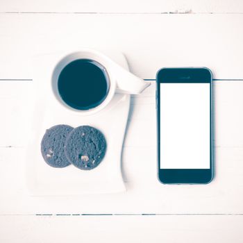 coffee cup with cookie and phone on white wood background vintage style