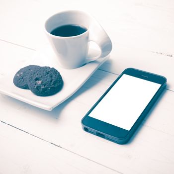 coffee cup with cookie and phone on white wood background vintage style