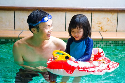 asian family in swim tube playing on swimming pool