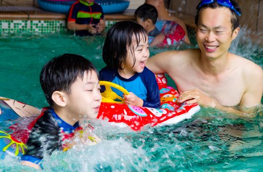 asian family in swim tube playing on swimming pool