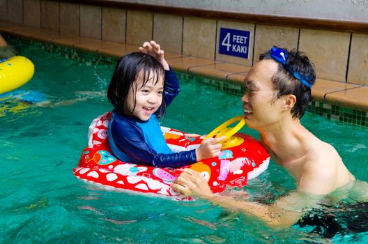 asian family in swim tube playing on swimming pool