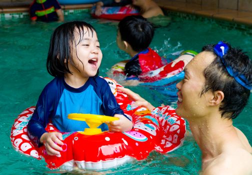 asian family in swim tube playing on swimming pool