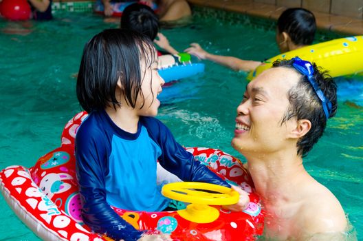 asian family in swim tube playing on swimming pool