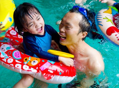 asian family in swim tube playing on swimming pool