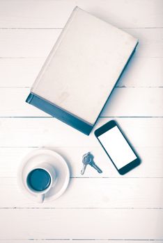 coffee cup with phone,key and stack of book on white wood table vintage style
