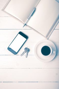 coffee cup with phone, key and open notebook on white wood table vintage style