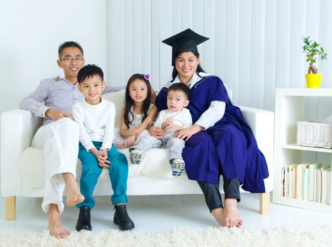 Asian mother in graduation gown.Taking photo with family.