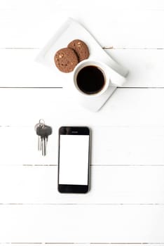 coffee cup with cookie,phone and key on white wood table