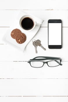 coffee cup with cookie,phone,eyeglasses and key on white wood background
