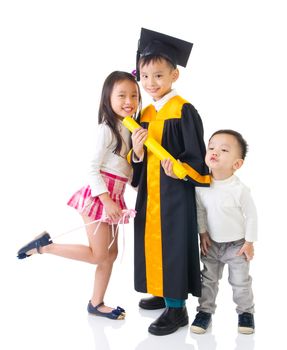 Asian school kid graduate in graduation gown and cap. Taking photo with sister and brother.