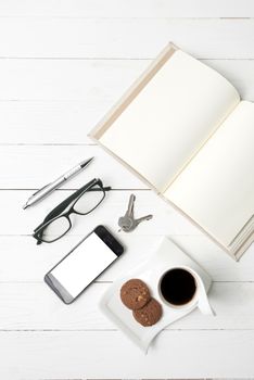 coffee cup with cookie,phone,open notebook and eyeglasses on white wood table