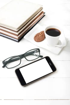 coffee cup with cookie,phone,stack of book and eyeglasses on white wood table