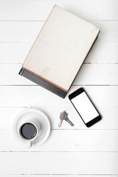 coffee cup with phone,key and stack of book on white wood table