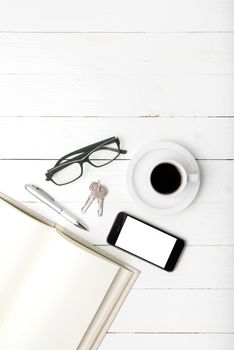 coffee cup with phone, key,eyeglasses and open notebook on white wood table